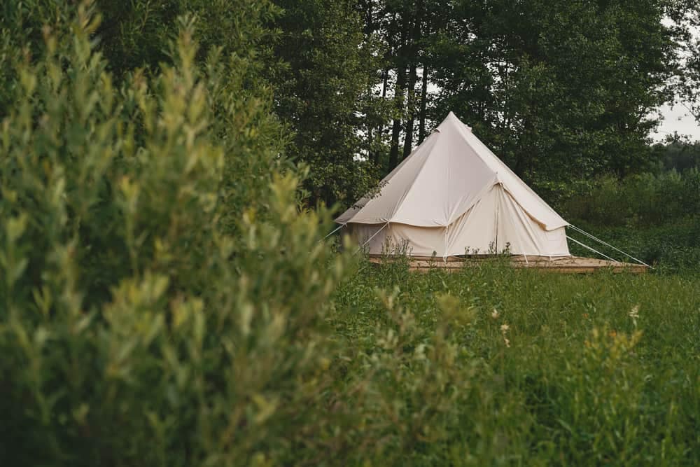 As part of the CampCalNOW Glamping Program, a white tent sits in the middle of a grassy field.