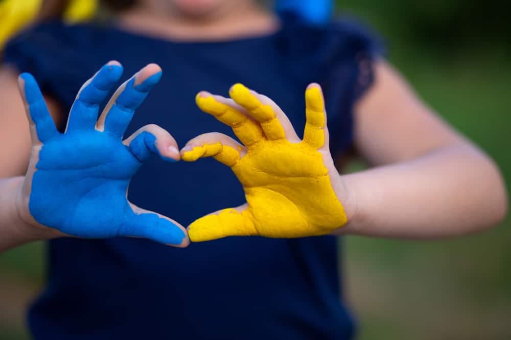 A little girl with painted hands making a heart shape at Preston Caravans.