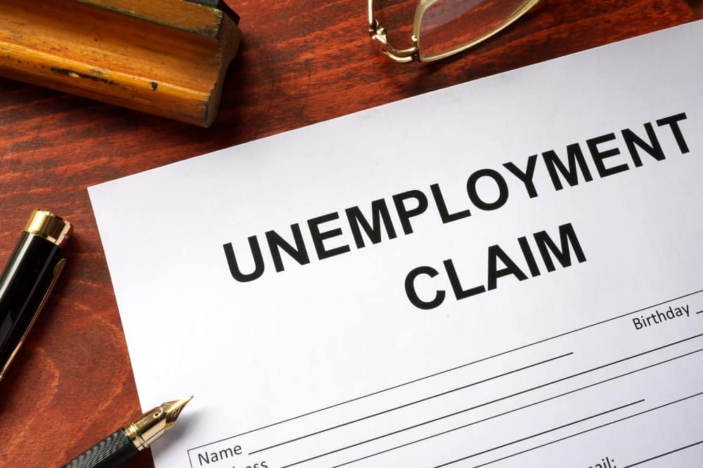 Historically low unemployment claims on a table with a pen and glasses.