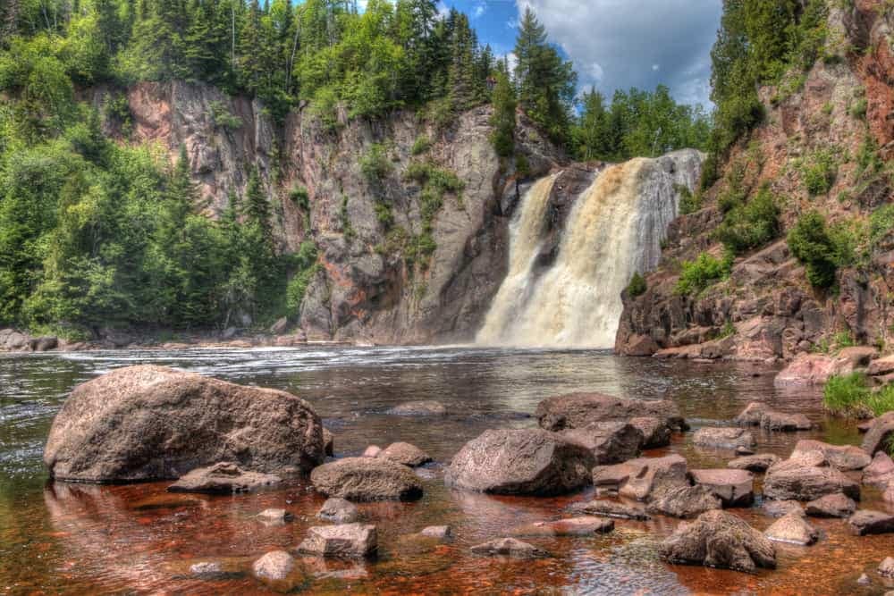 Tettegouche State Park reopens with a picturesque waterfall surrounded by rocks and trees.