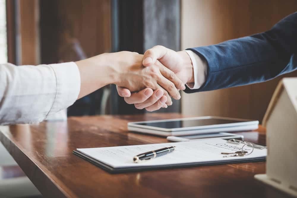 Two people shaking hands over a desk at Manteca Trailer and Motorhomes, an RV Retailer.