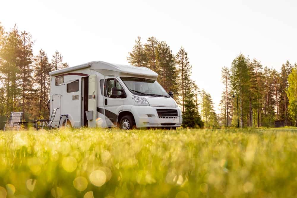 An RV adds to the serene atmosphere of a grassy field.