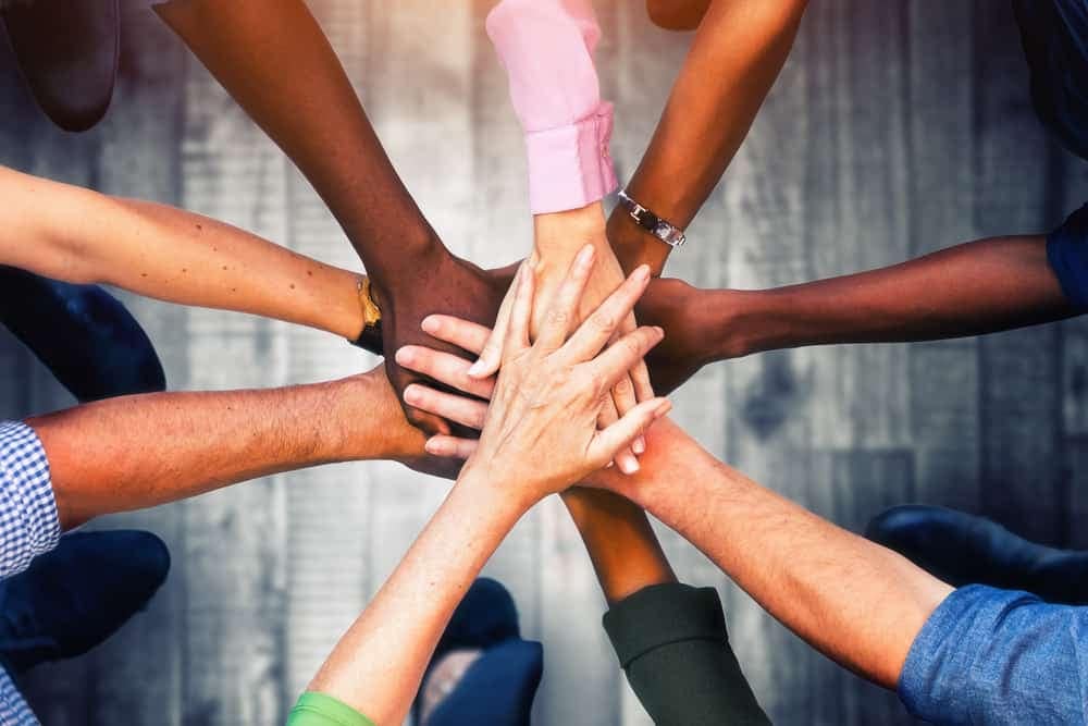 A group of people promoting economic growth by putting their hands together in a circle.