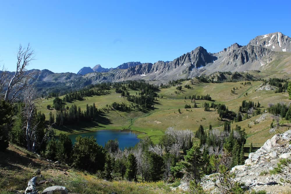 A lake in the Beaverhead-Deerlodge National Forest with trees and mountains in the background, perfect for Memorial Day Weekend camping.