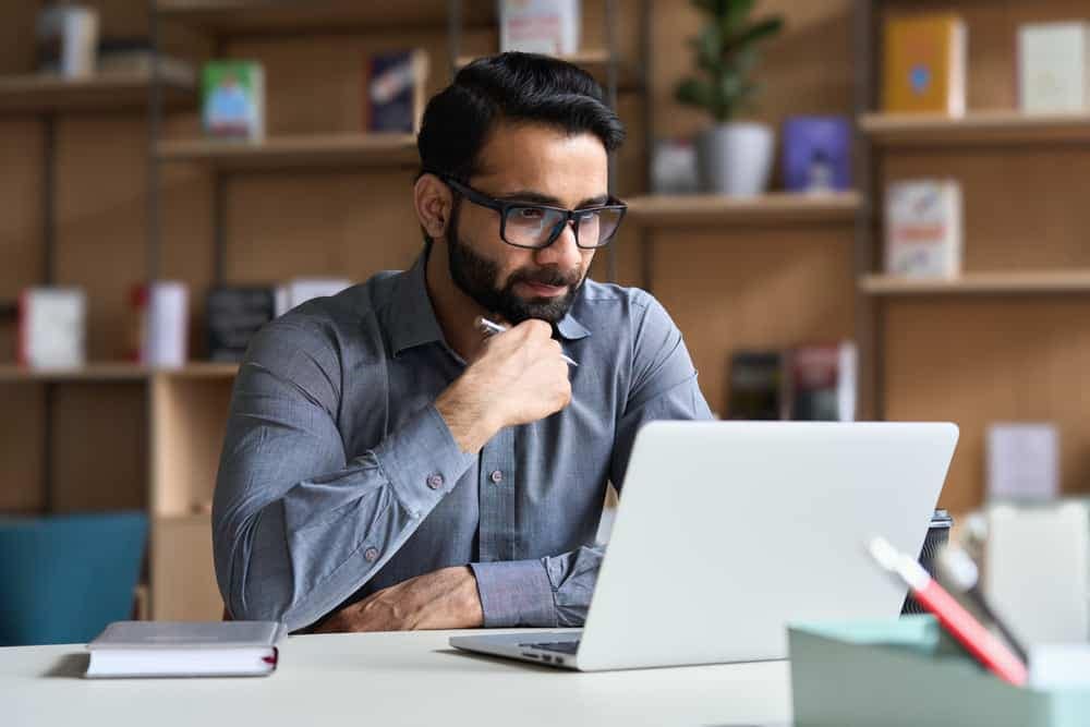 A man conducting a webinar on market analysis for the campground industry while sitting in front of a laptop in an office.