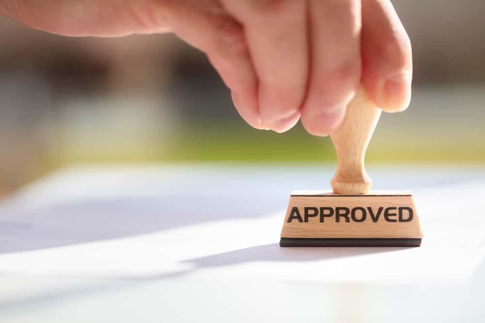 The Texas City Council member holding a rubber stamp with the word "approved" on it enthusiastically supports the implementation of new RV Park rules.