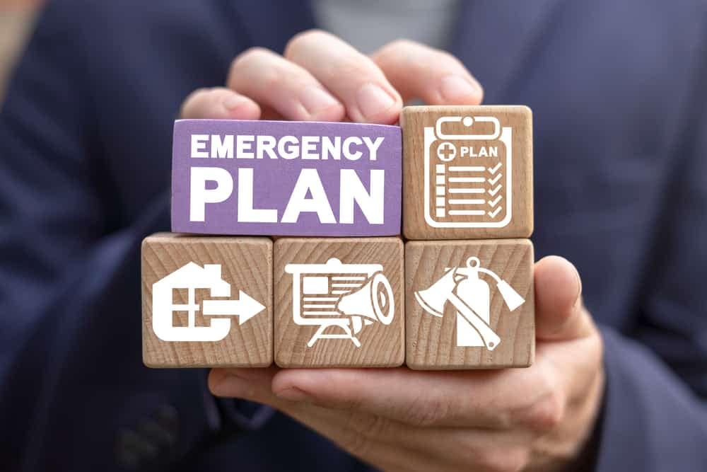 In British Columbia, a businessman strategically holds wooden blocks with the words "emergency plan" in preparation for effective emergency management within the tourism industry.