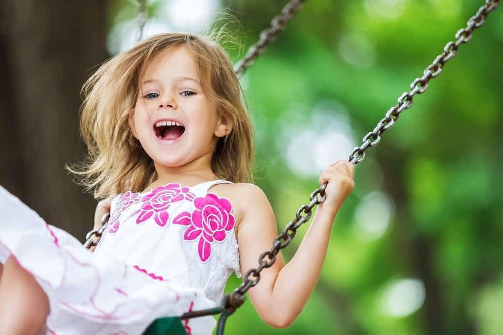 In Centennial Park, a little girl is happily swinging on a Ralph C. Wilson Jr. funded playground development.