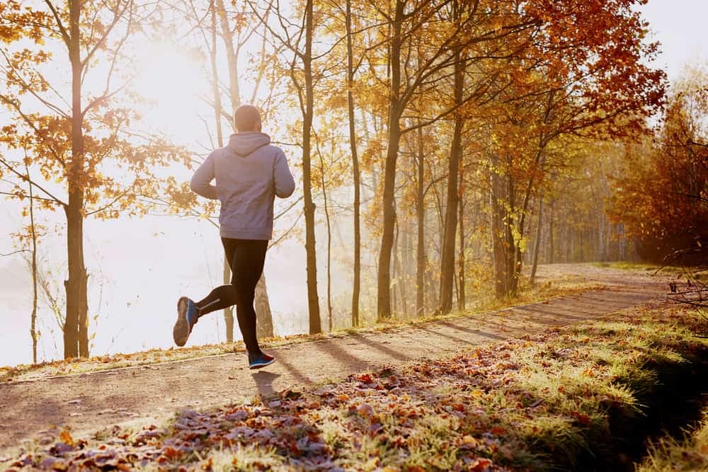 A man is jogging through the Tater Tot Trail in Ontario during the fall.