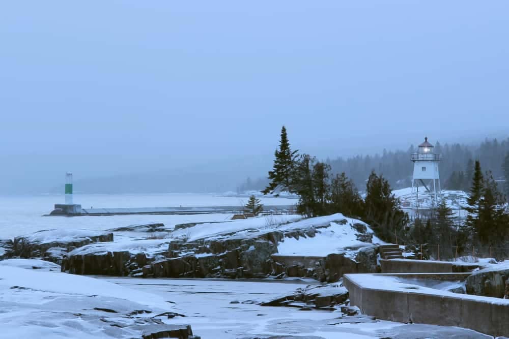 A snowy scene in Northern Minnesota with a lighthouse in the background.