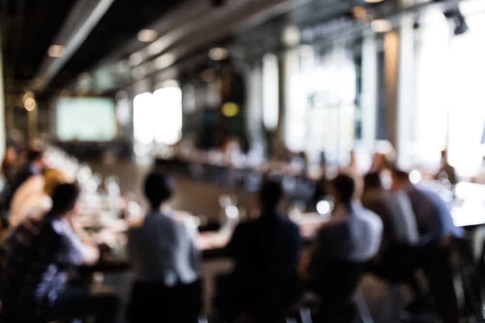 A blurry image of a group of people at a Move America Week conference.
