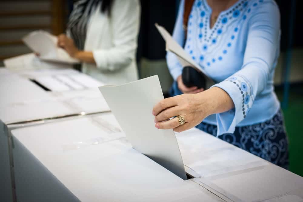 A woman is putting paper into a voting box in Alabama.
