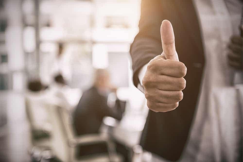 A businessman giving a thumbs up in front of a group of people at Keweenaw Waters Resort.