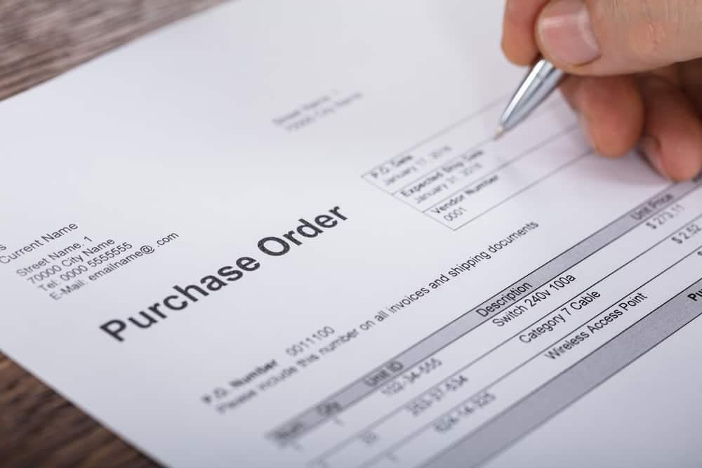 A person writing a purchase order for a $1.5 million order on paper for Cortes Campers.