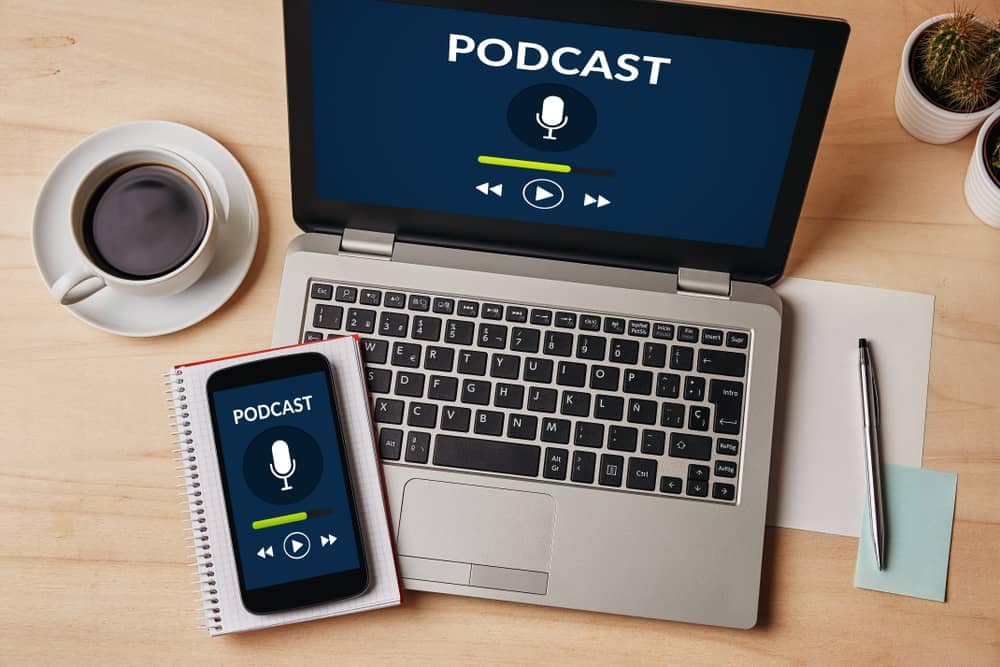 A laptop with a microphone and a cup of coffee next to it, perfect for MC Fireside Chats or Outdoor Hospitality.