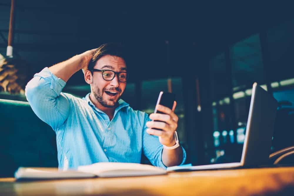 A man is sitting at a table in Australia, looking at his phone.