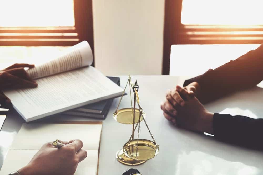 Two people sitting at a table with a book and scales at Surf and Stream Campground in Ocean County while Tenant Sues.