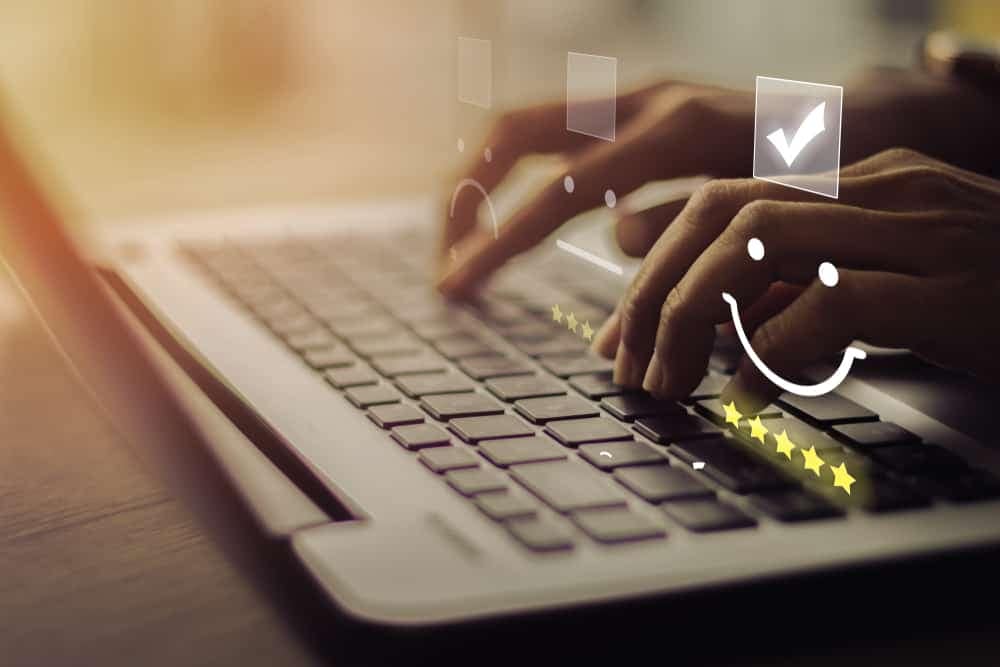 A person typing on a laptop while completing the Dealer Satisfaction Index (DSI) Survey for RVDA with a smiley face on it.