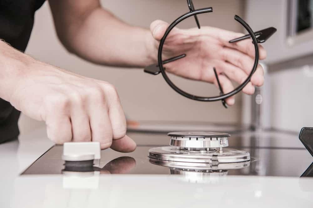 A man is putting a ring on a stove top from the Swift 500 Series Appliances.
