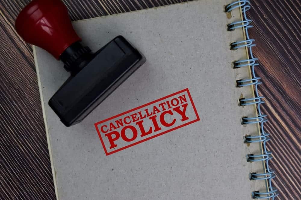 A rubber stamp with the word cancellation policy on top of a notebook for Campsite Reservations.