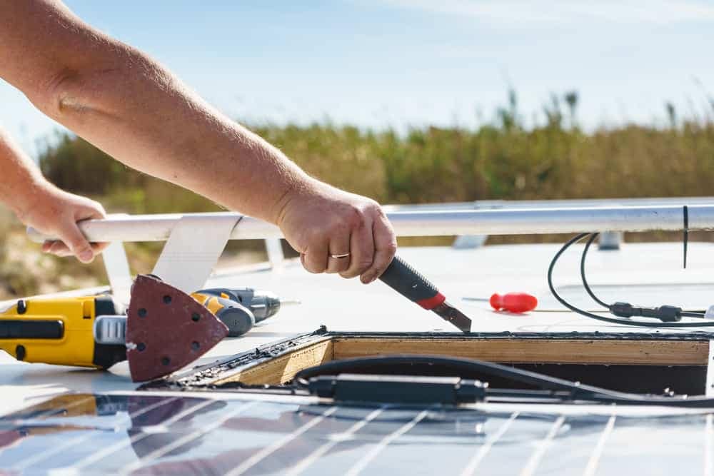 A man is working on a solar panel on a boat, exploring off-grid living with EcoFlow power solutions.