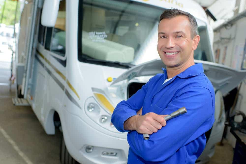 A man standing in front of a Valvoline servicen expansion rv in a garage.