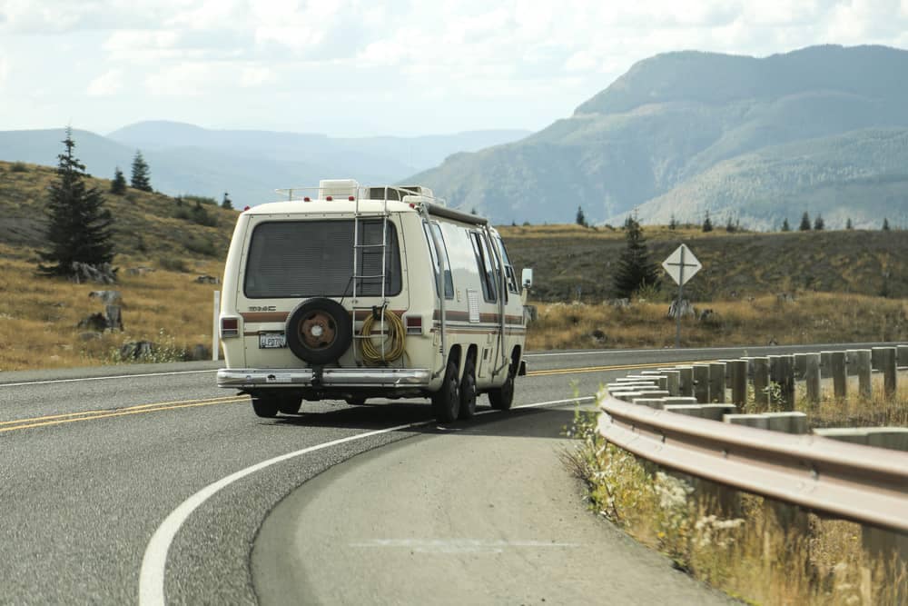 A van driving down a road with majestic mountains in the background.