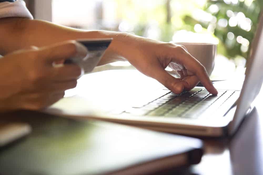 A person using a laptop for online credit card reservations.
