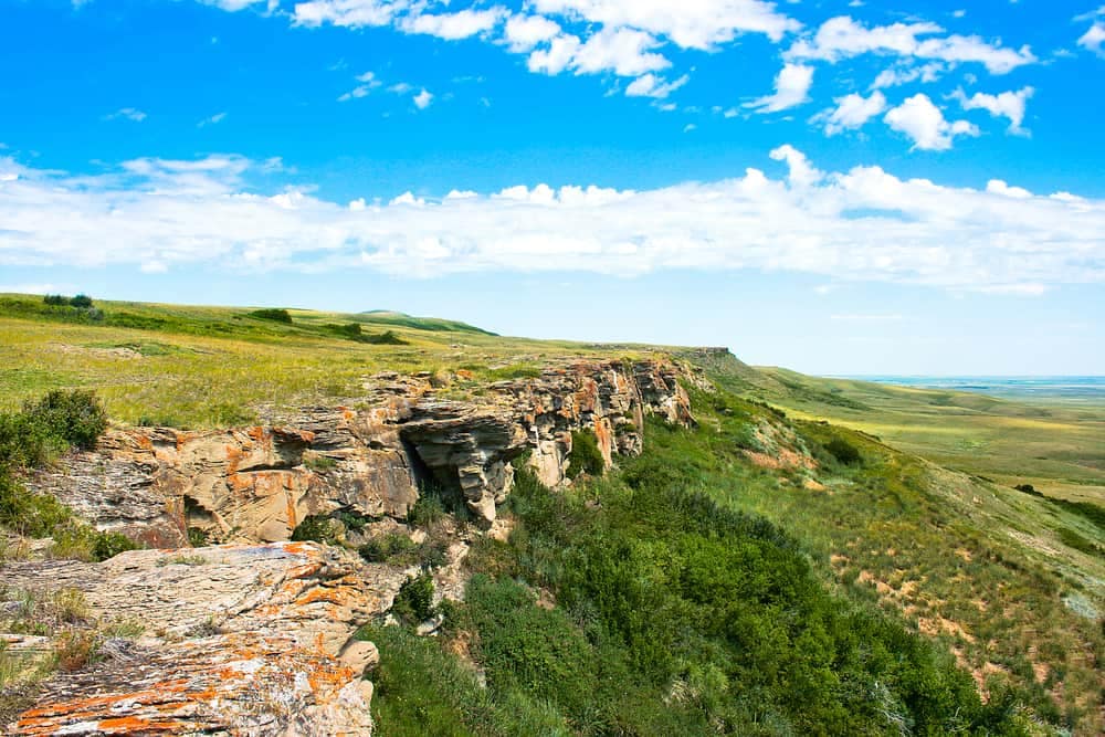 A rocky cliff in Buffalo Pound Provincial Park overlooking a grassy plain.
