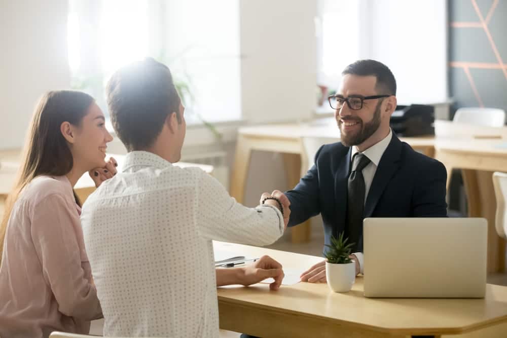 Two people shaking hands at a table in an expanding office, discussing Garden City RV Insurance and FCIS Insurance.