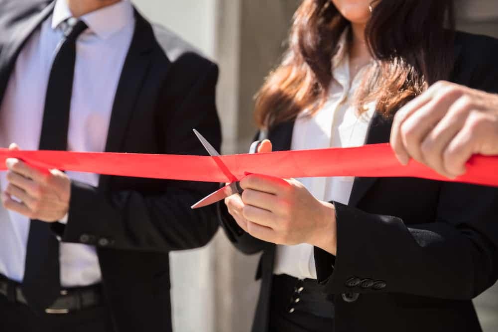 Two business people cutting a red ribbon at the grand opening ceremony of Weeley Bridge Holiday Park, celebrating the launch of their new Caravan Homes.