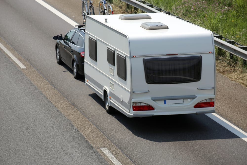 A truck-friendly RV on the side of the road with a car behind it, providing towing education and training.