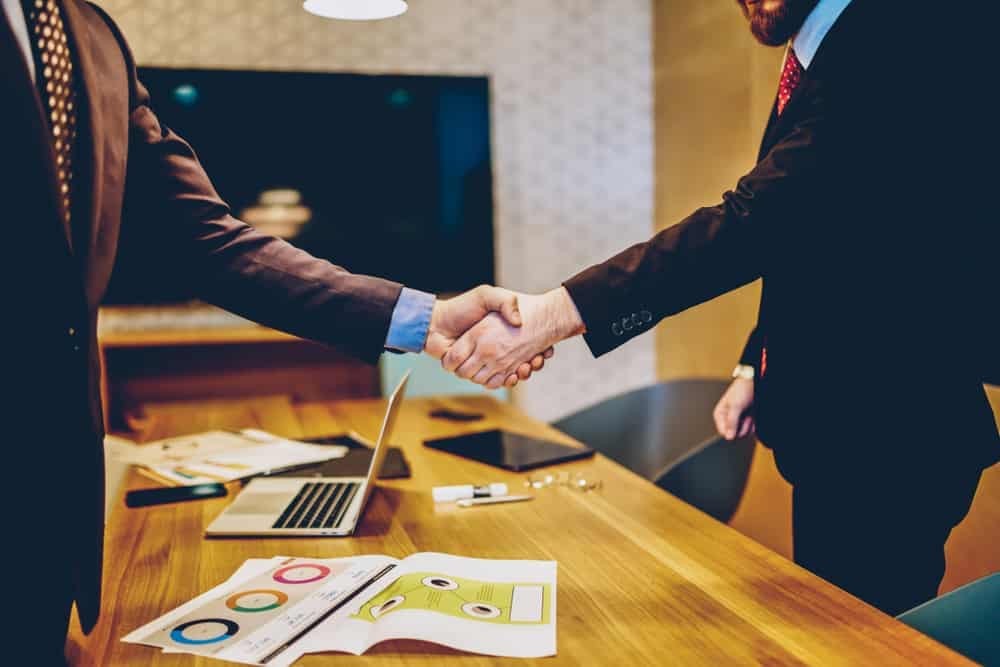 Two businessmen shaking hands over a table at the RVIA Regulatory & Safety Compliance Seminar, sponsored by RVIA.
