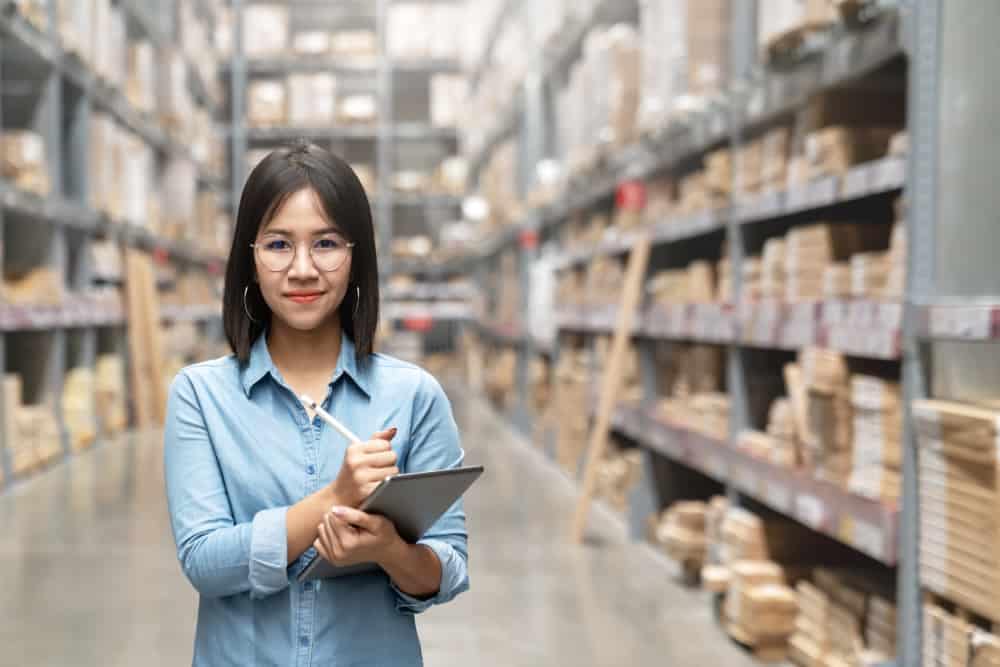 A woman in a warehouse in Germany holding a clipboard for sales records.