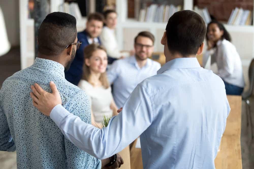 A group of people in an office, including the CEO, engaged in conversation.