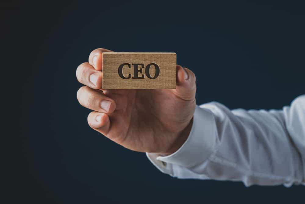 John North, the CEO of Lazydays, confidently holds up a wooden board with the word "CEO" on it.
