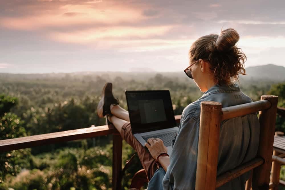 A CONY Campground Views Partner enjoys discounted fees while sitting on a wooden deck with a laptop.