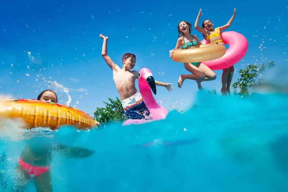 A group of kids enjoying the Splash Zone feature at Cornwall Holiday Park while playing in the water with inflatable floats.