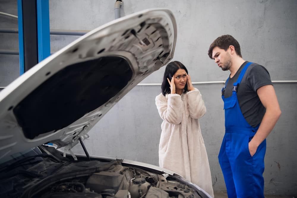 A man and woman inspecting the hood of a car in the Caravan Industry.