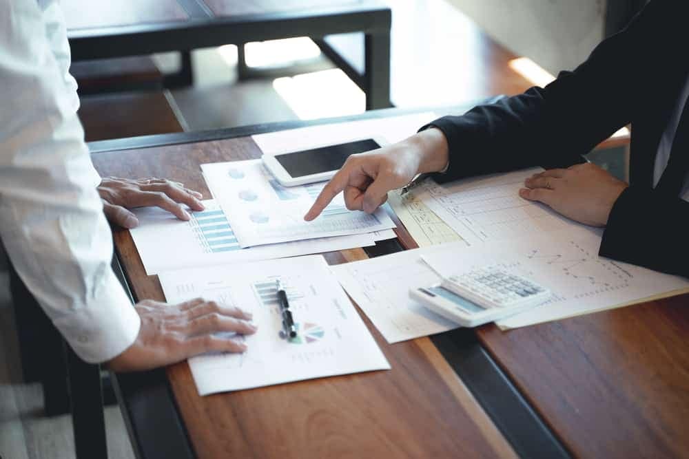 Two business people sitting at a table reviewing Second Quarter 2022 results with papers spread out.