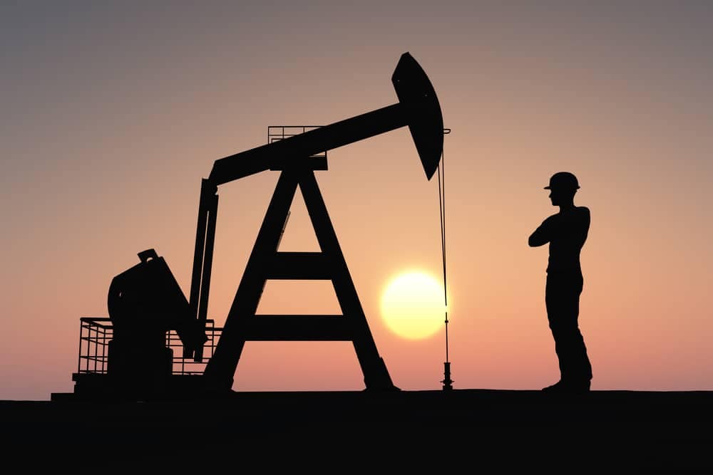 A man is standing in front of an oil pump in Canada.