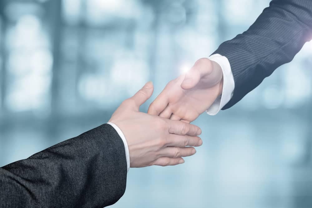 Two businessmen shaking hands in front of a blurred background at a business conference.