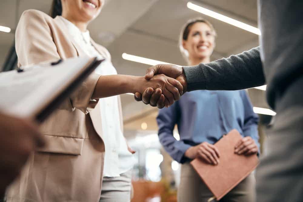 Jennifer Lee, the CFO of Pathfinder, shaking hands with another business person in an office.
