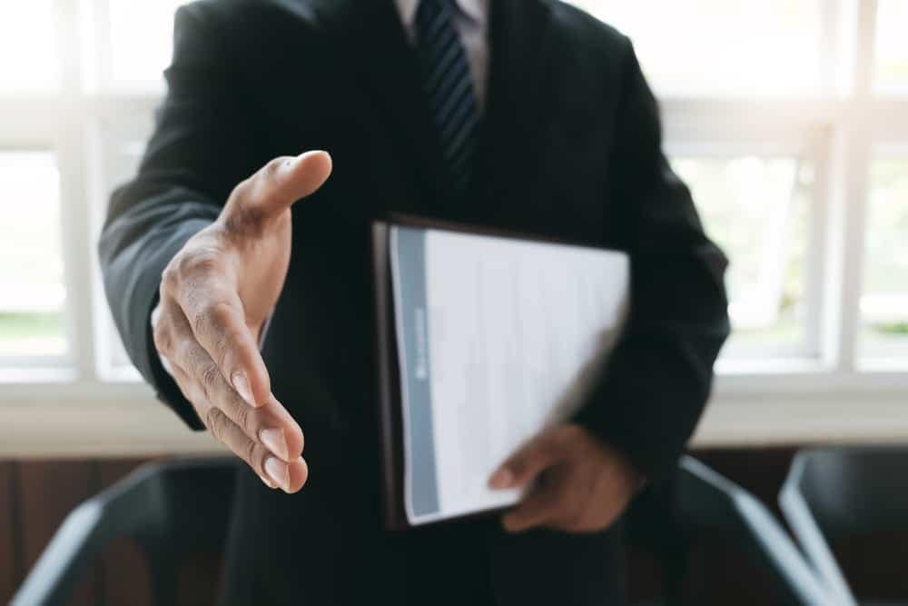 A BMPro businessman in a suit is handing over a folder to an RV.