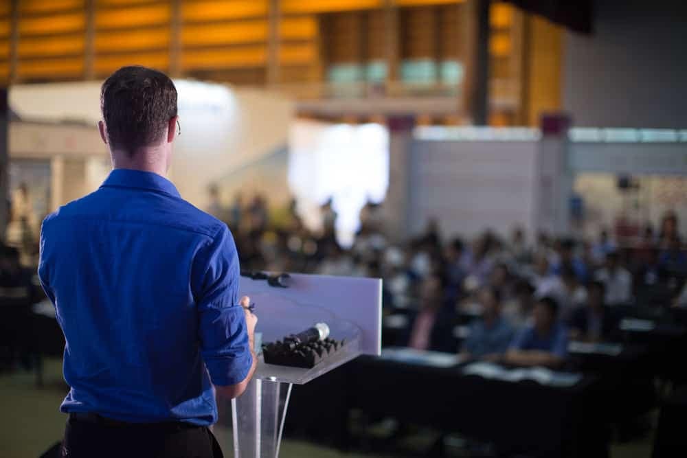 A presenter giving a speech on growth capital at a TSX Venture event.