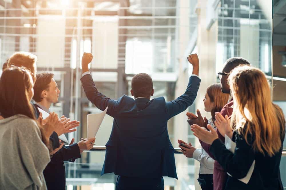 A group of business people clapping in front of a building in Australia, celebrating the growth of Leisure-Tec.