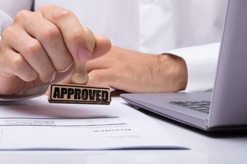 At the serene Newberry RV Park, a man proudly wields a rubber stamp with the word "approved" on it.