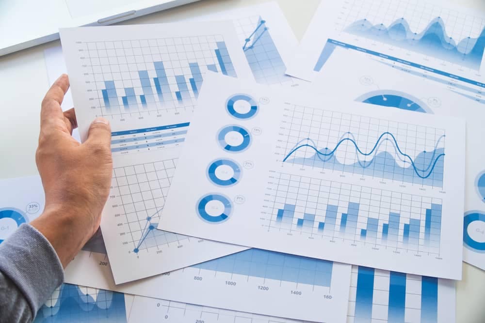 A man is pointing at some financial graphs on a desk during the second quarter.