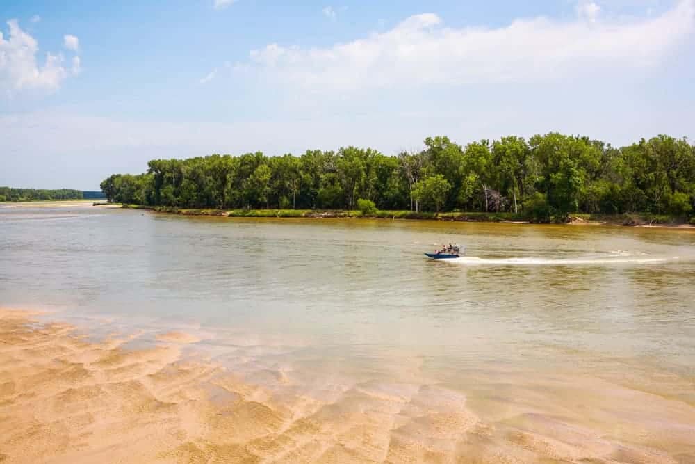 A jet ski is traveling down a river with trees in the background, capturing the exhilarating experience of a thrilling water ride.