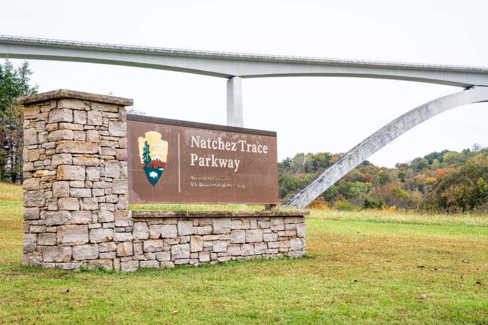 A sign in front of the Natchez Trace bridge that says wildfire trail pathway.